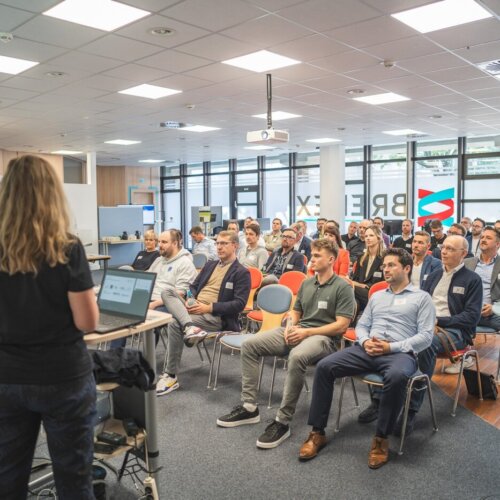 Person hält Vortrag vor einer Gruppe von Menschen in einem Konferenzraum.